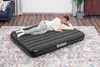 A man is lying on an inflatable mattress on a rug in a living room. Náhled obrázku produktu