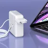 A white laptop charger and cable are placed next to an open laptop on a purple surface. Podgląd zdjęcia produktu