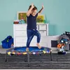 A young boy is joyfully jumping on a small trampoline in a child's room. The room has a dresser, framed artwork, and toys. Anteprima dell’immagine prodotto