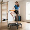 A woman is exercising on a mini trampoline in a room with exercise equipment. Podgląd zdjęcia produktu