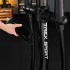 A hand is holding a black water bottle near a black exercise machine. Produktbild-Vorschau