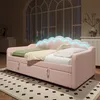 A pink daybed with a scalloped headboard featuring LED lighting, set in a dimly lit room with a large arched window in the background. Produktbild-Vorschau