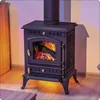 A black cast iron wood-burning stove with a fire burning inside, set in a room with wooden flooring and a wooden cabinet. Voir les images du produit