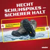 A pair of boots with shoe spikes attached, placed on ice. Produktbild-Vorschau