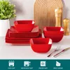 A set of red ceramic dishes and bowls are arranged on a white countertop, with a wooden cutting board and salt and pepper grinders in the background. Icons indicating oven, microwave, freezer, and space-saving safety are displayed at the bottom. Náhled obrázku produktu