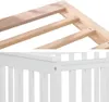 A close-up view of the corner of a baby crib, showing both the unfinished wood frame and the painted white slats and top rail. Produktbild-Vorschau