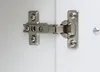 A close-up view of a cabinet hinge attached to a white surface. Produktbild-Vorschau