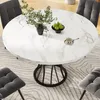 A round marble dining table with black legs, surrounded by gray upholstered chairs, set in a dining room with a patterned rug. Náhled obrázku produktu