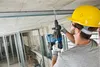 A construction worker is drilling into a concrete ceiling. Produktbild-Vorschau