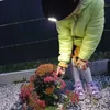 A child is examining a plant in a garden setting. Produktbild-Vorschau
