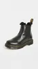 A black Dr. Martens boot with faux fur lining is shown against a white background. Produktbild-Vorschau