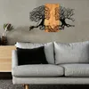 A metal wall art piece depicting two faces merging with trees, mounted on a wall above a sofa. Produktbild-Vorschau