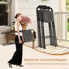 A woman is carrying a folded stool on a porch, with a stack of stools in the background. Produktbild-Vorschau
