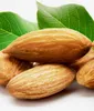 A close-up of several almonds with green leaves in the background. Produktbild-Vorschau