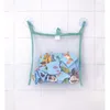 A mesh bag filled with bath puzzle pieces hangs from suction cups on a tiled wall. Produktbild-Vorschau