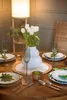 A dining table set for a meal with white tulips in a vase, plates, glasses, and cutlery. Náhľad obrázku produktu