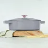 A gray cast iron pot with a pink knob sits on a wooden board with wheat stalks and a cloth. Anteprima dell’immagine prodotto