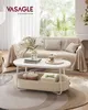 A coffee table with items on it, placed in a living room setting with a couch and plants in the background. Produktbild-Vorschau