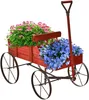 A red wooden wagon filled with pink and blue flowers, set against a white background. Produktbild-Vorschau