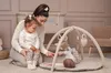 A mother is playing with her two young children on a play mat. Produktbild-Vorschau