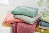 A stack of folded blankets in various colors on a cork surface. Produktbild-Vorschau