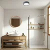 A modern bathroom with a wooden vanity, sink, mirror, and a walk-in shower with shelves. Produktbild-Vorschau