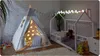 A child's bedroom with a teepee tent and a house-shaped bed, decorated with string lights. Produktbild-Vorschau