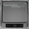 A close-up of a gray electronic device with text overlays indicating temperature settings and display options. Voir les images du produit