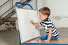 A young boy is drawing on a whiteboard. Náhled obrázku produktu