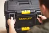 A person is shown opening a black and yellow Stanley tool box. Voir les images du produit