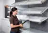 A woman is using a steam cleaner on a set of shelves. Voir les images du produit