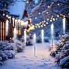 A winter scene with icicle-shaped LED lights strung across a snowy garden path, with a house in the background. Náhled obrázku produktu