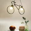 A bicycle-shaped pendant light hangs above a table with decorative items. Podgląd zdjęcia produktu