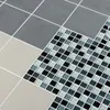 A close-up view of different types of tiles, including large gray tiles and small mosaic tiles in black, white, and blue. Produktbild-Vorschau