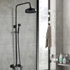 A black shower fixture is mounted on a tiled wall next to a window. Produktbild-Vorschau