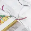 A close-up view of a sheer curtain with a floral pattern and a book with text. Produktbild-Vorschau