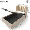 A beige upholstered bed frame with the mattress support open, revealing storage space underneath. Dimensions are indicated with measurement lines and numbers. Produktbild-Vorschau
