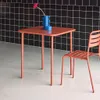 A small square table and a chair are set against a black tiled wall. Anteprima dell’immagine prodotto