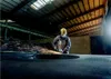 A worker in a factory is using an angle grinder, creating sparks. Podgląd zdjęcia produktu