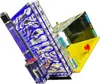 A close-up, angled view of a clear acrylic ant farm with blue and silver internal structures, a purple water reservoir on the left, and a yellow feeding area on the right. Náhľad obrázku produktu