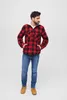 A man wearing a red and black plaid jacket and blue jeans stands against a white background. Náhled obrázku produktu