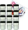 A set of glass jars with black lids, arranged in rows, with a recipe booklet and a packet of jelly powder in the background. Produktbild-Vorschau