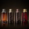 Four bottles of Hugo Boss The Scent for Him fragrances are displayed in a studio setting with a dark, reflective background. Náhľad obrázku produktu