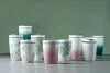 A collection of ceramic travel mugs with various designs, arranged on a flat surface against a green background. Voir les images du produit