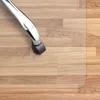 A close-up view of a chair caster on a transparent floor mat over a wood-look floor. Náhled obrázku produktu