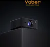A black projector is placed on a black cube against a dark background, with the brand logo and product type at the top. Anteprima dell’immagine prodotto