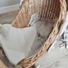A wicker bassinet with bedding on a wooden floor. Anteprima dell’immagine prodotto