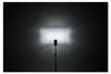 A studio shot of a flash unit on a stand, illuminating a wall with a bright rectangular beam of light. Podgląd zdjęcia produktu