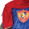 Roter Umhang mit goldener Einfassung über blauer Tunika mit Löwenwappen. Produktbild-Vorschau