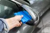 A person is using a blue silicone squeegee to dry a car's side mirror. Produktbild-Vorschau